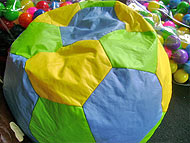 Foto 
de puff em formato de bola verde, amarela e azul