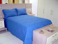 Foto de uma cama com edredon e travesseiros