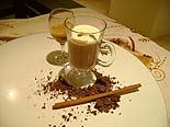 Foto do chocolate quente em uma ta?a e ao lado uma ta?a de licor de creme de cacau em cima de uma mesa decorada
