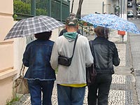 Foto de pessoas andando com sombrinhas