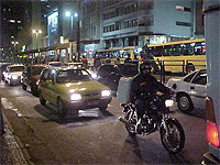 Foto de motoboy dirigindo à noite no trânsito de JF