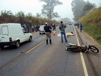 Moto acidentada, carros e pessoas na estrada