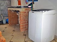 Foto da área de serviço da casa, mostrando a máquina de lavar e pia