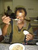 homem almo?ando, oferencendo uma colher de sopa