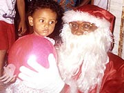 Carlos vestido de Papai Noel e entregando presente ?s crian?as