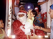 Carlos vestido de Papai Noel e entregando presente ?s crian?as