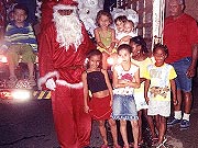 Carlos vestido de Papai Noel e entregando presente ?s crian?as