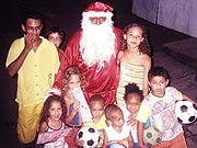 Carlos vestido de Papai Noel e entregando presente ?s crian?as