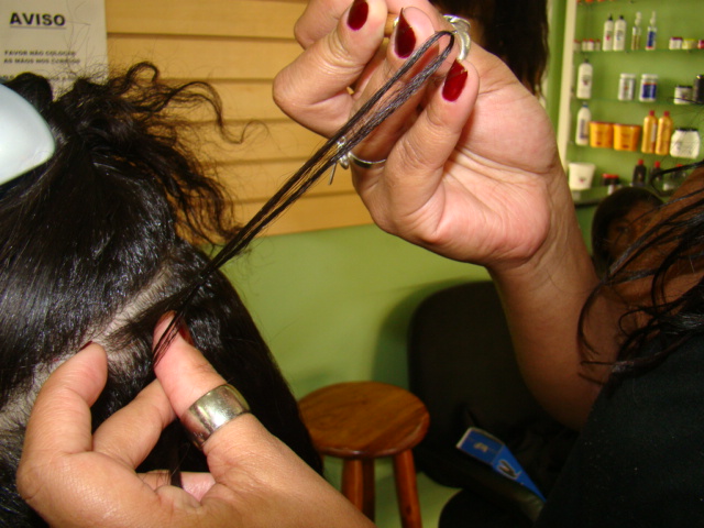Foto de Flávia aplicando megahair em uma mulher