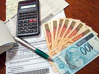 Foto de uma mesa com contas, calculadora e dinheiro