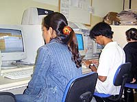 Foto com três pessoas, cada uma acessando um computador