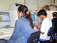 Foto com tr?s pessoas, cada uma acessando um computador