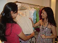 Foto ilustrando vendedora de loja de roupas mostrando uma
blusa para uma cliente
