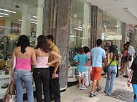 Foto de várias pessoas olhando a vitrine de uma loja de calçados