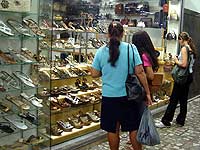 Pessoas olhando vitrine com cal?ados e bolsas