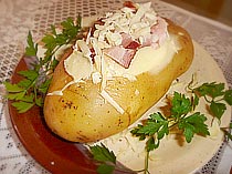 Foto da batata recheada com creme pronta, com ramos de salsa 
enfeitando o prato
