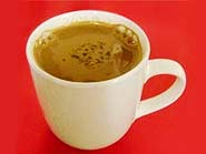 Foto do chocolate quente em uma ta?a com duas pimentas malaguetas secas por cima e canela em pau