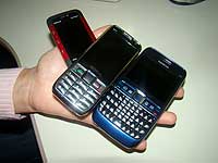 pessoa segurando três celulares