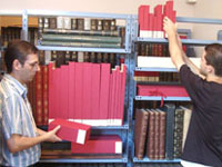 Foto de pessoas mexendo no acervo da Biblioteca