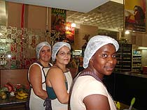 Foto das tr?s cozinheiras finalistas 
do I Concurso de Culin?ria da Alimenta??o Escolar, promovido pela Secretaria de Educa??o da 
prefeitura de Juiz de Fora. Elas est?o em uma cozinha do Espa?o Gourmet do supermercado Bahamas